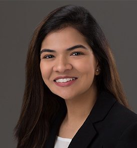 A woman in business attire smiles confidently, embodying the professionalism of a Relationship Associate against a neutral backdrop.