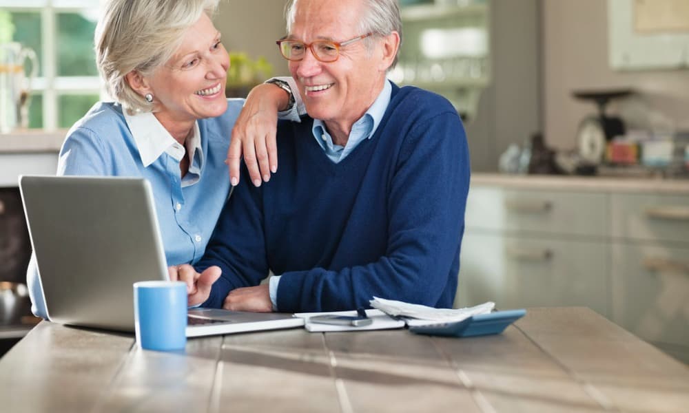 An elderly couple smiling after finding a realistic retirement calculator.