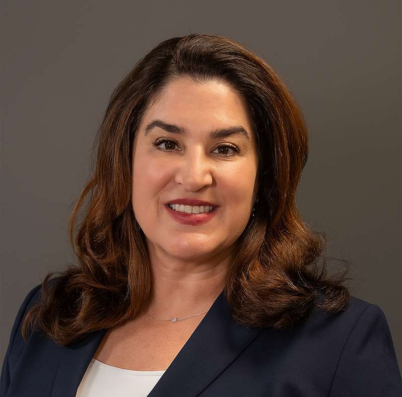 Torry Dell smiling, wearing a dark blazer and white top, against a plain background.